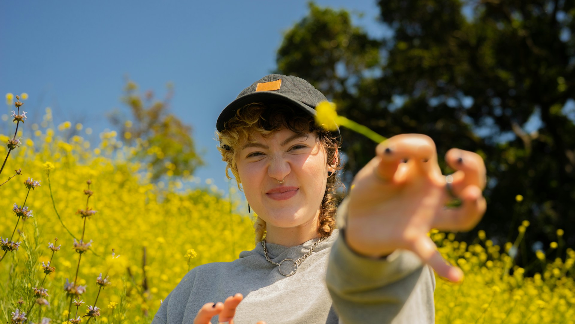 Photo of a person holding a dandelion and smiling in a field of dandelions. Eat for Life provides nutrition for ADHD in Raleigh NC