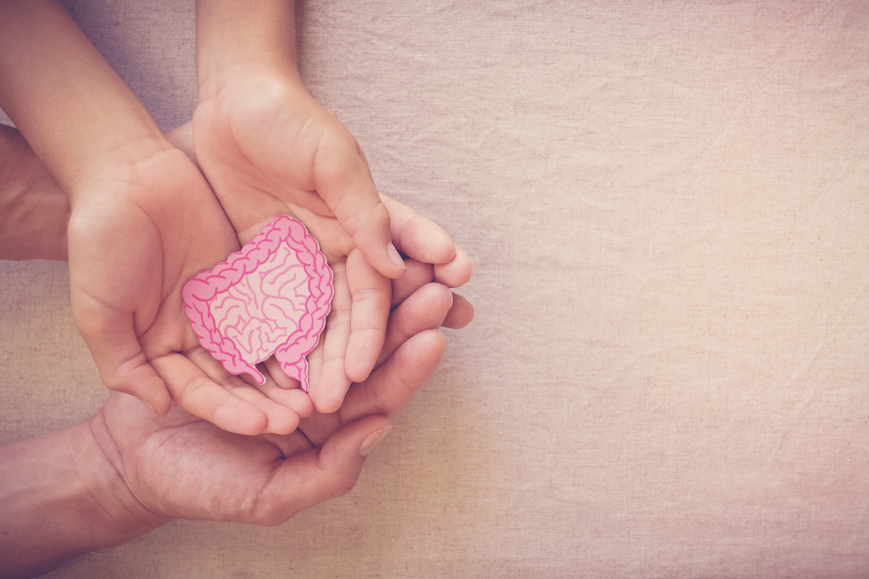 A child holds a paper cut out of an intestine, while an adult holds their hands. Eat for life helps with gut health diet in Raleigh and Durham.