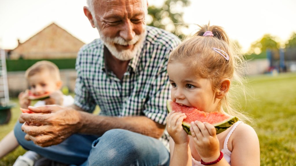 Three generations enjoying watermelon together – highlighting family wellness and healthy aging through functional nutrition