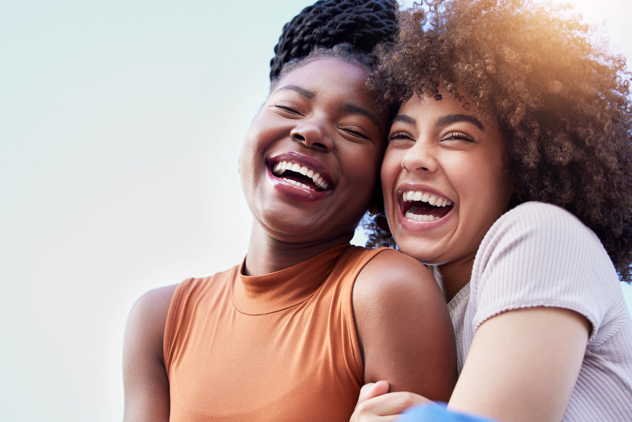 Two young women hug each other as they smile and laugh outside. Eat for life offers nutritional counseling for eating disorders in Durham.