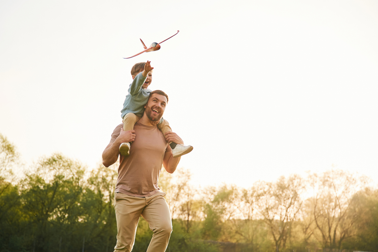 A father in son play in a field with a toy airplane. Eat for Life provides your child nutritionist in Durham support.