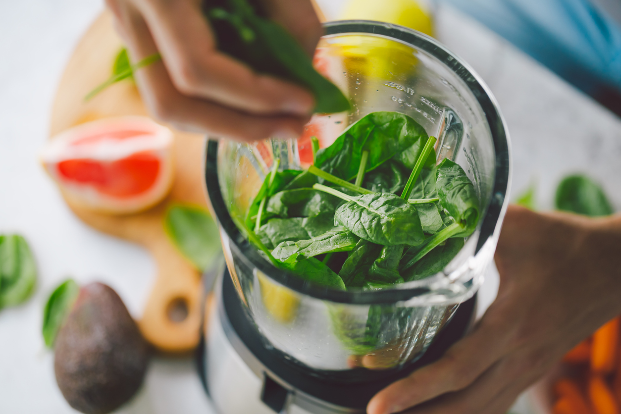 A person puts spinach in a blender with fresh fruits on the counter. How do you test for Candida overgrowth? We answer that here.