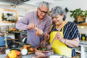 A senior couple is cooking in their kitchen together, they are both smiling. Pyrrole disorder is little known and often missed.