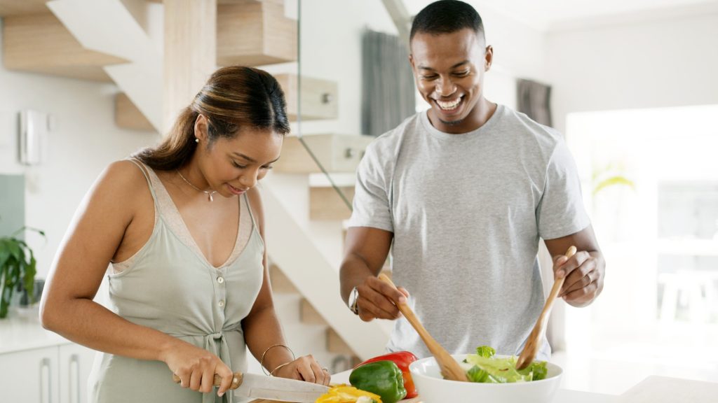 A happy couple cooks in the kitchen. Eat for Life provides pyrrole disorder nutrition counseling and cookbooks.